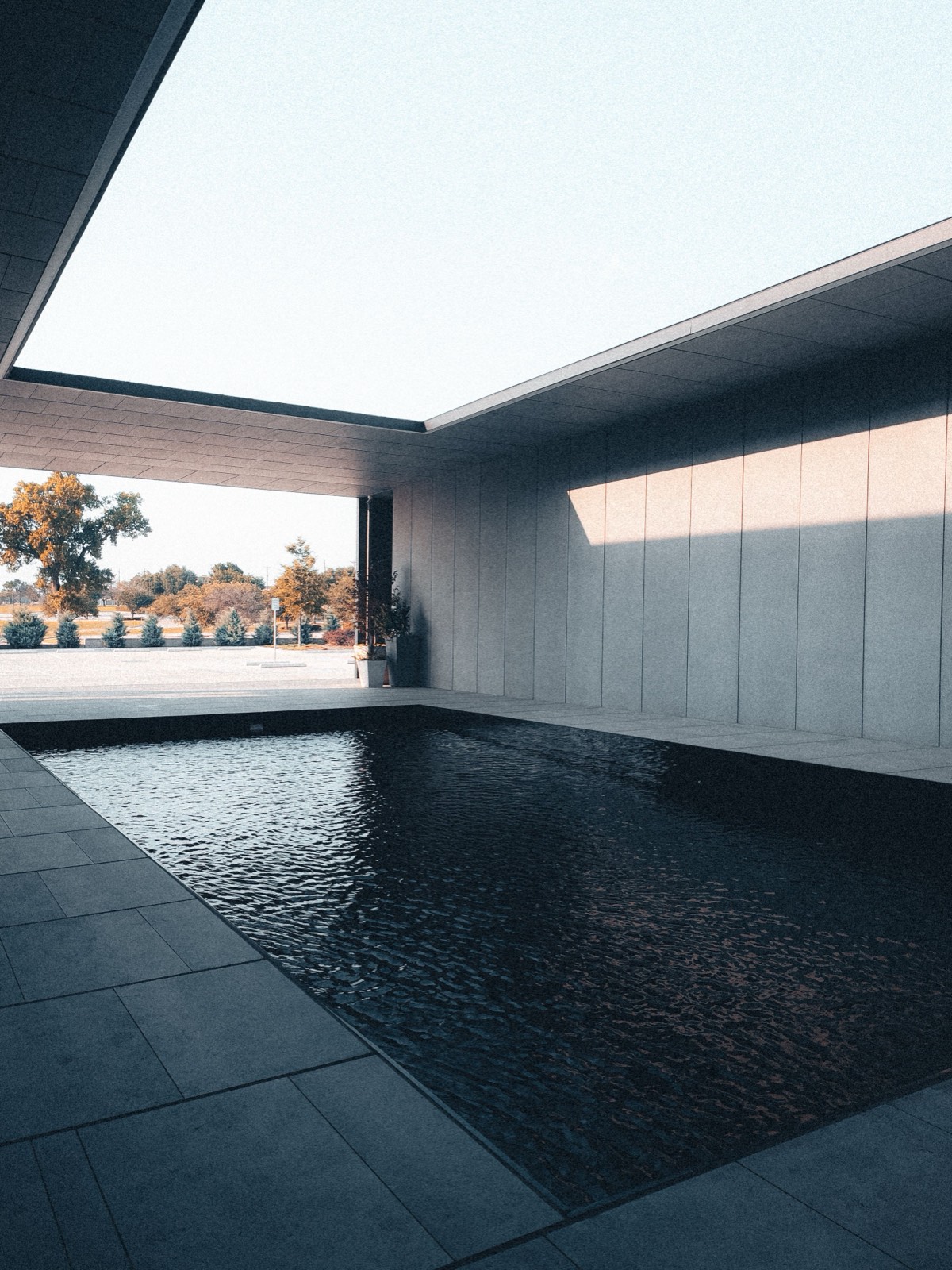 Minimalist concrete pool with dark reflective water, framed by clean architectural walls